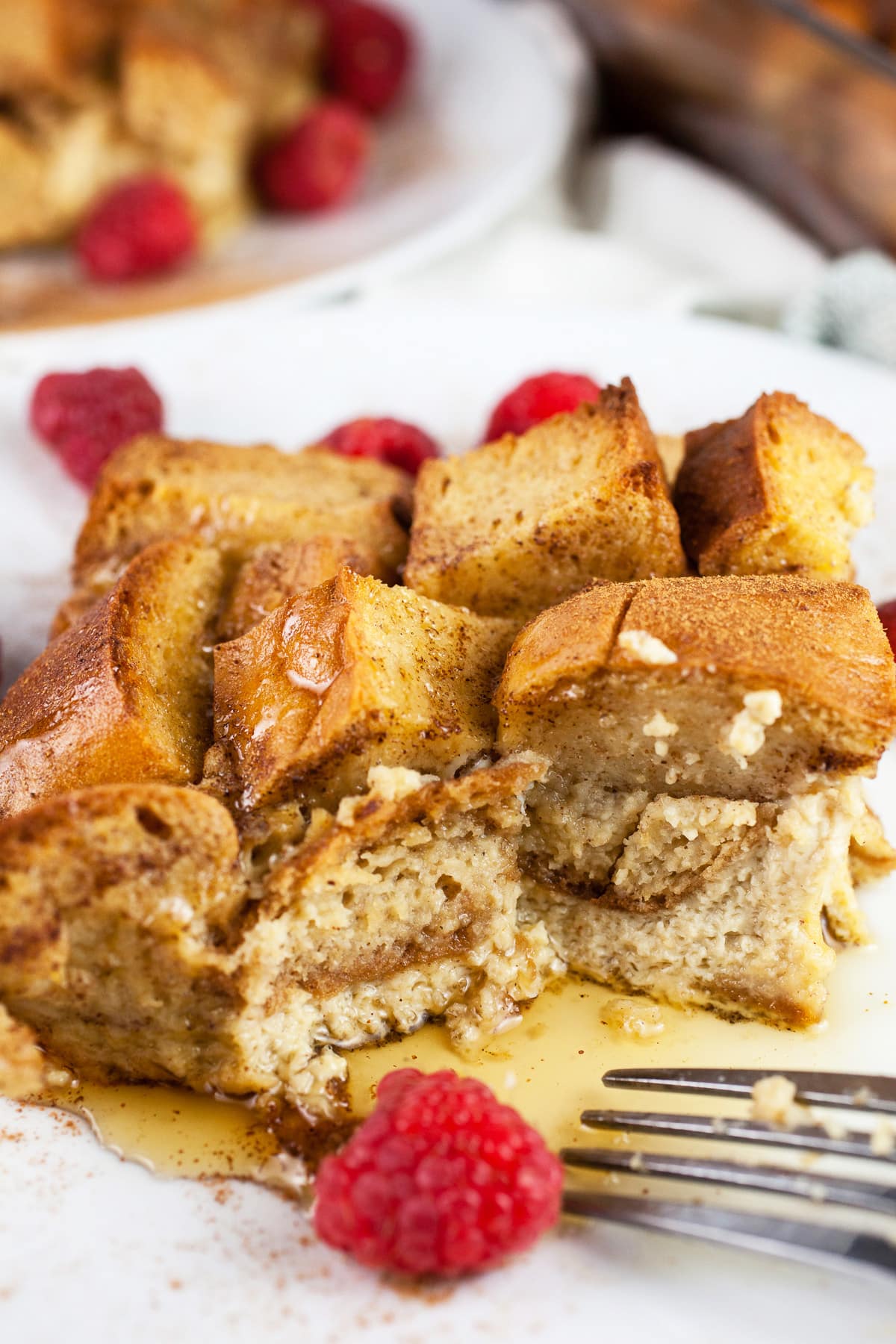 Piece of French toast casserole on white plate with fork.