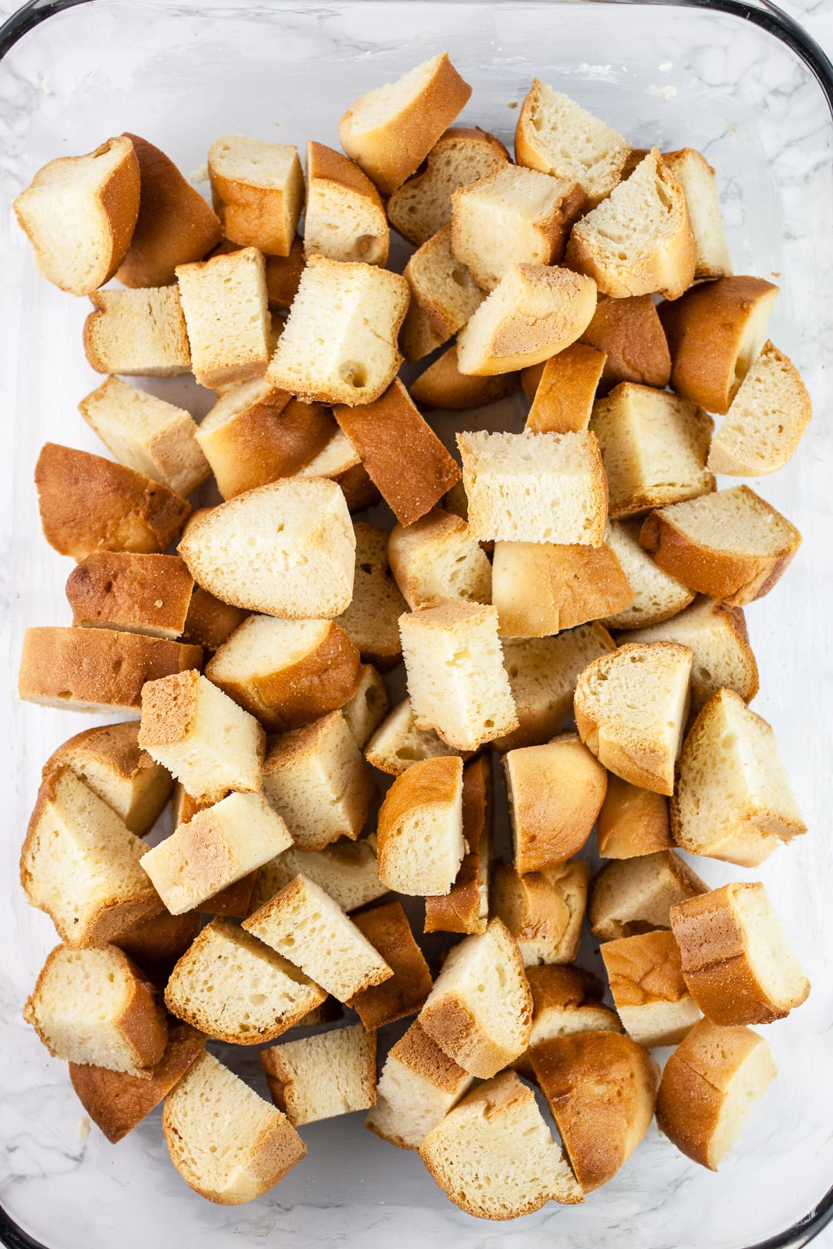 Brioche bread cubes in glass casserole dish.