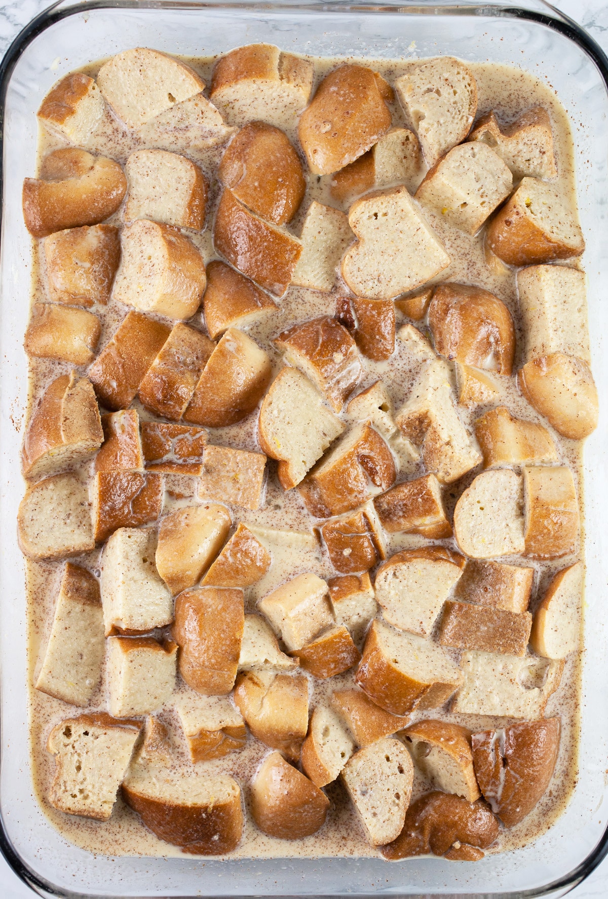 Unsoaked bread and egg mixture in glass casserole dish.