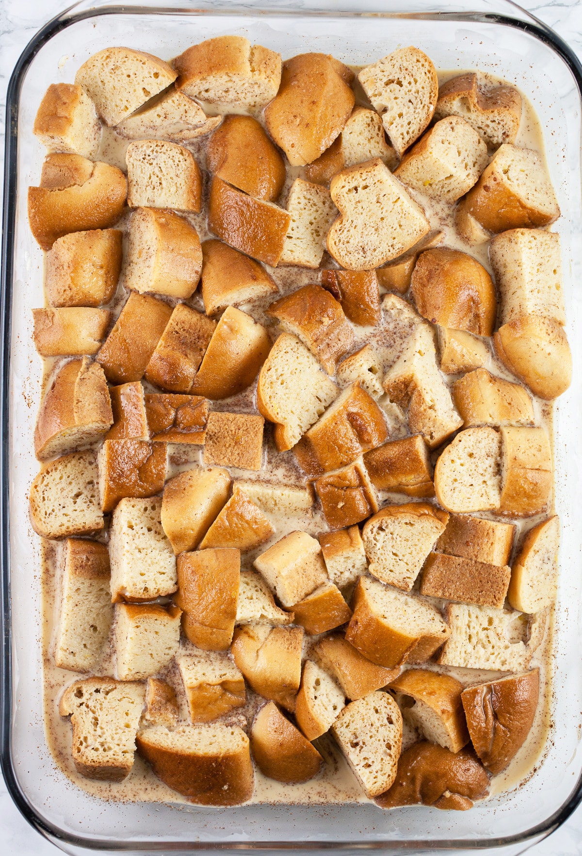 Soaked bread and egg mixture in glass baking dish.