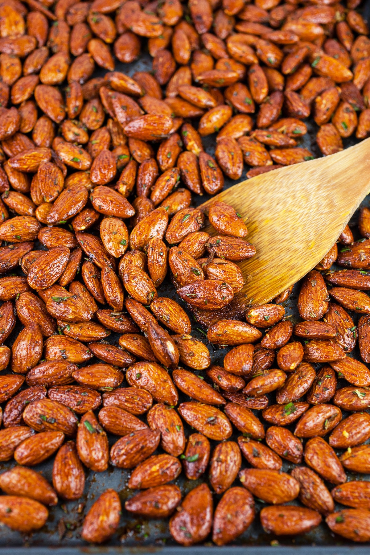 Raw almonds with olive oil and spices on baking sheet.