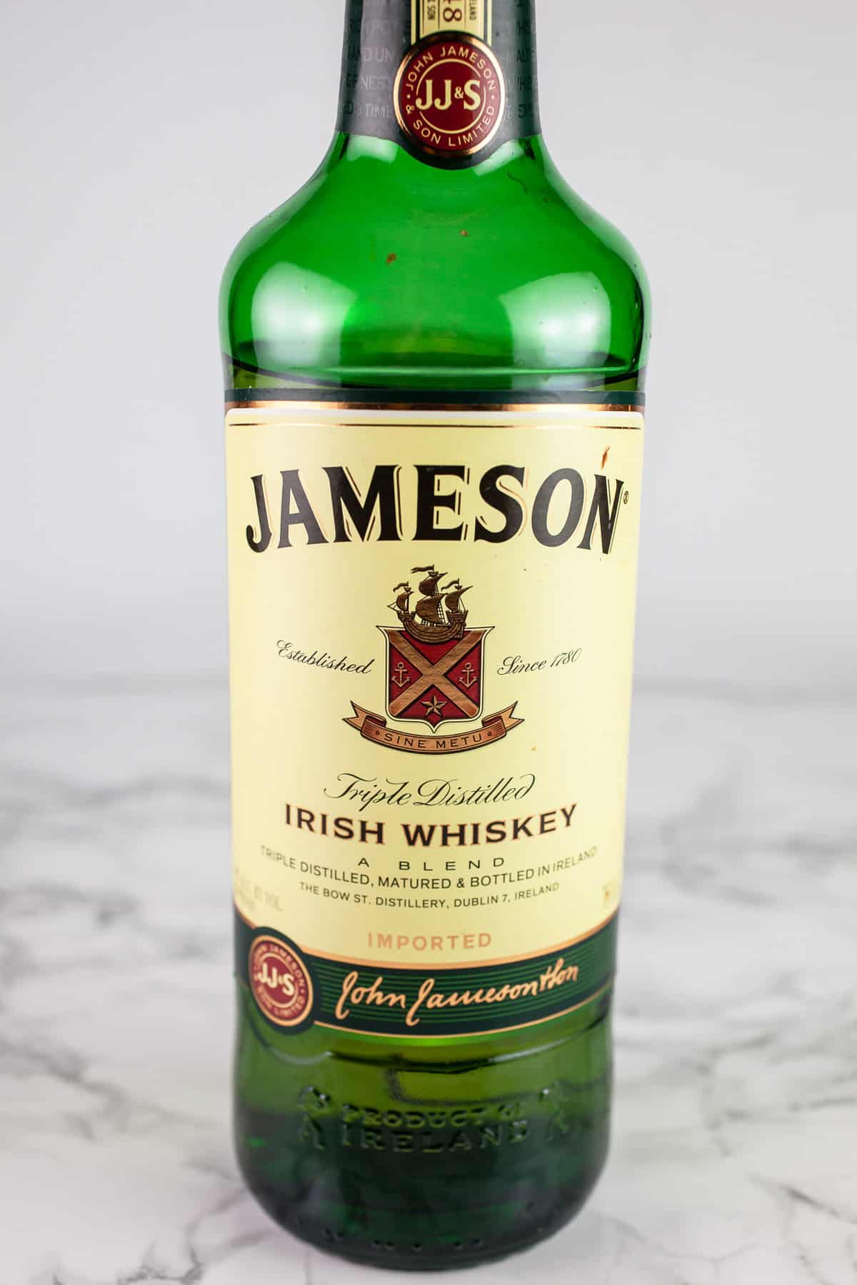 Bottle of Jameson Irish whiskey on white surface.