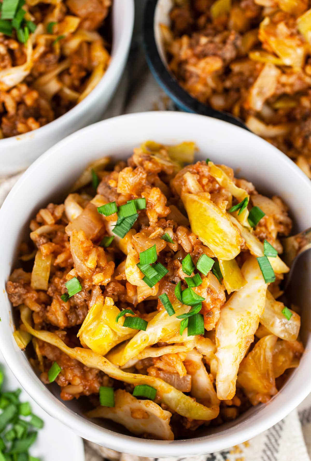 Cabbage roll in white bowls next to skillet.