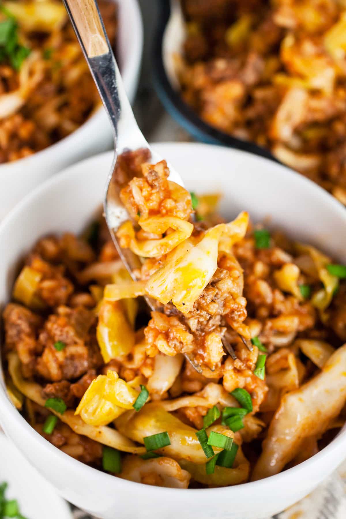 Forkful of unstuffed cabbage rolls lifted from white bowl.