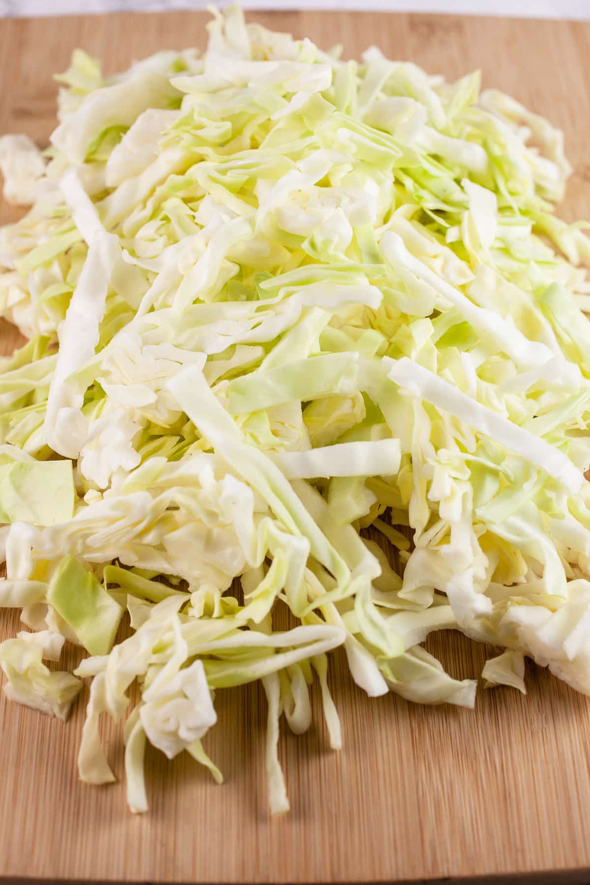 Shredded cabbage leaves on wooden cutting board.