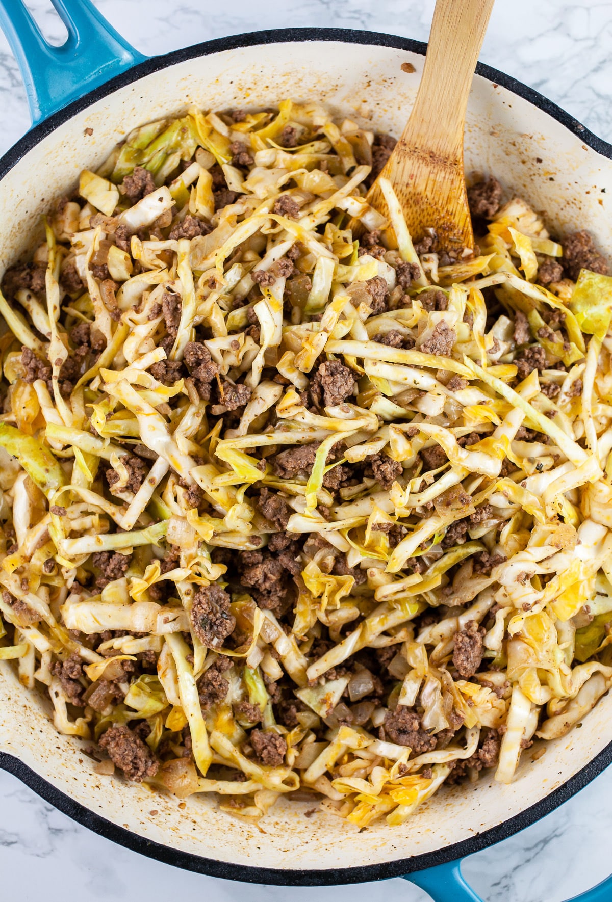 Cooked ground beef and cabbage mixture in skillet.