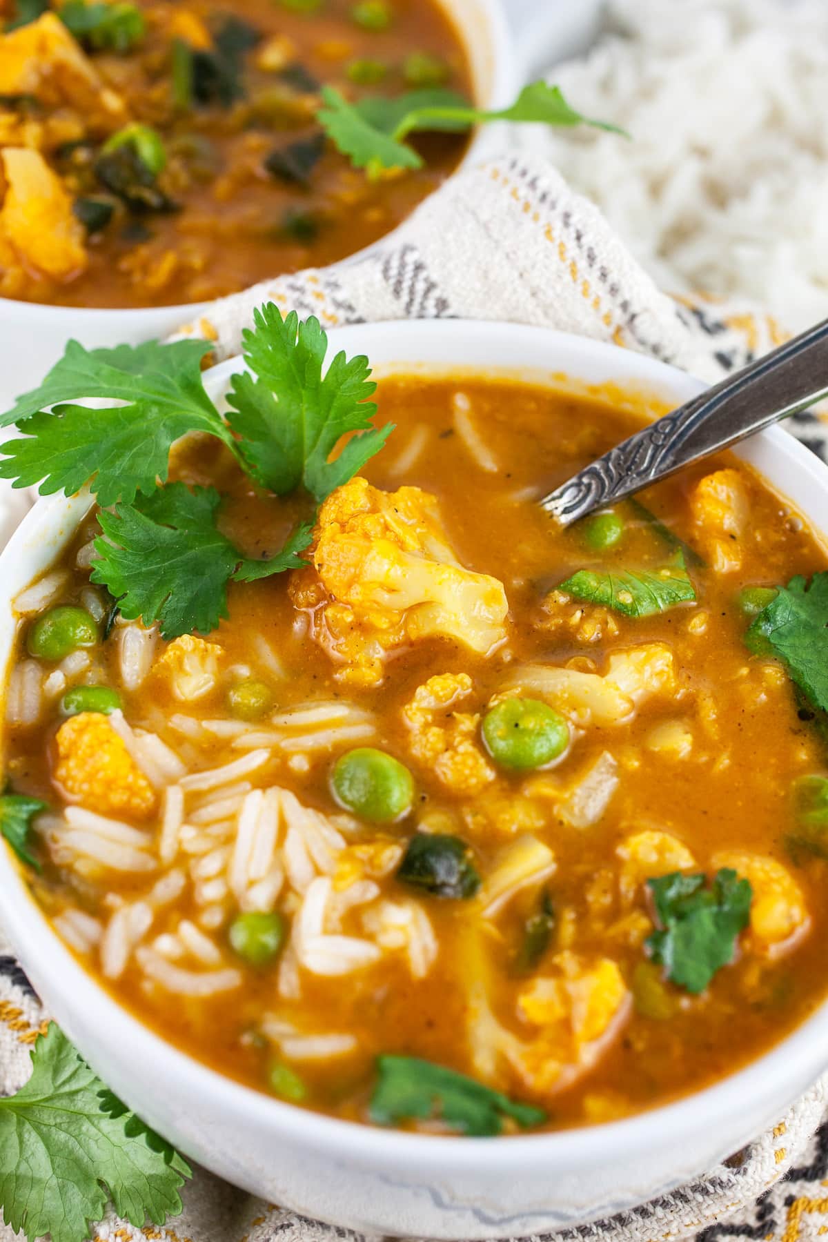 Cauliflower lentil soup with rice and cilantro in white bowls.