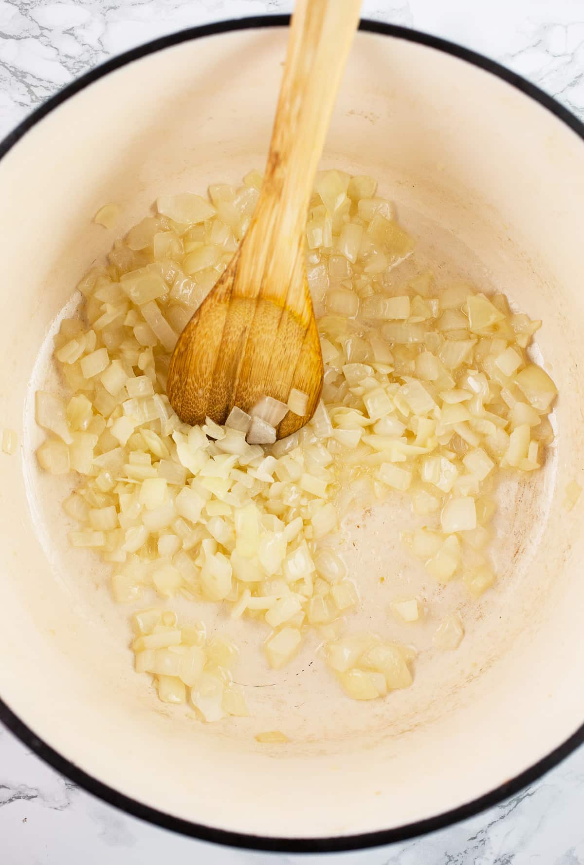 Minced garlic and onions sautéed in Dutch oven with wooden spoon.