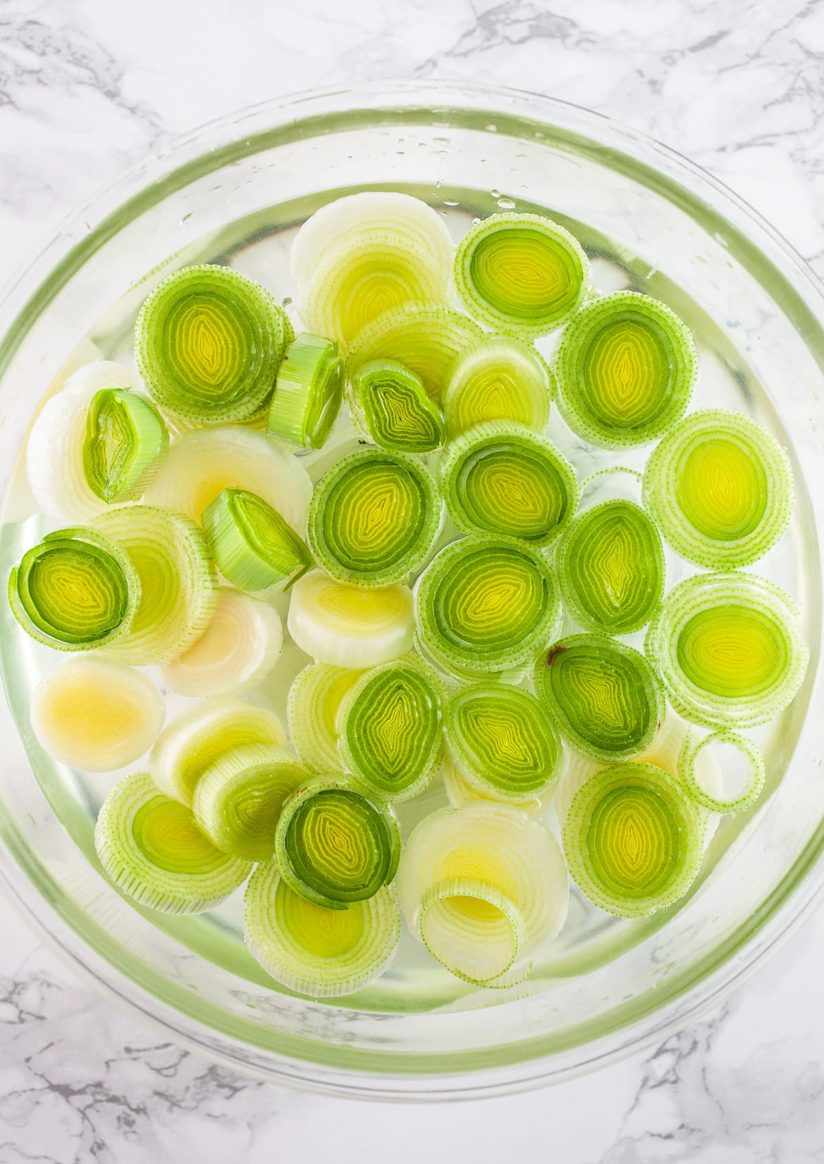 Sliced leeks in glass bowl of water.