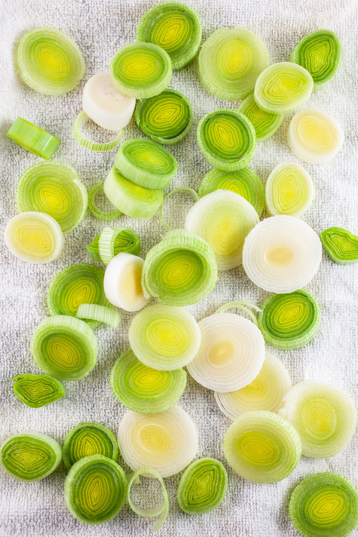 Sliced leeks drying on white cloth towel.