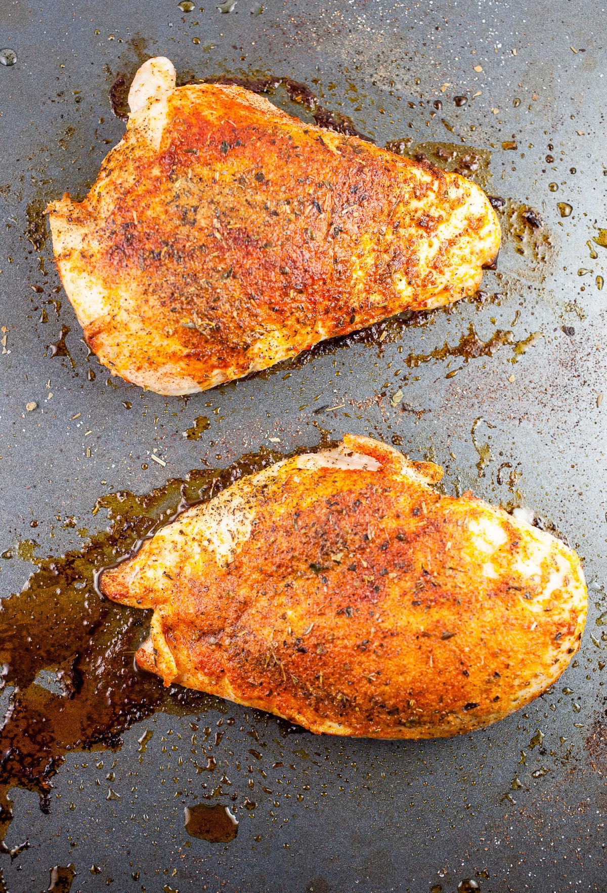 Cooked spiced chicken breasts on baking sheet.