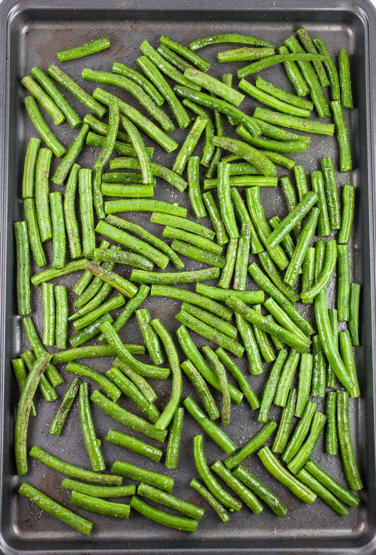 Uncooked green beans on baking sheet.