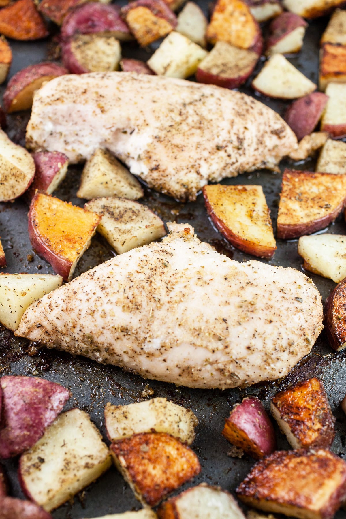 Roasted chicken and potatoes on baking sheet.