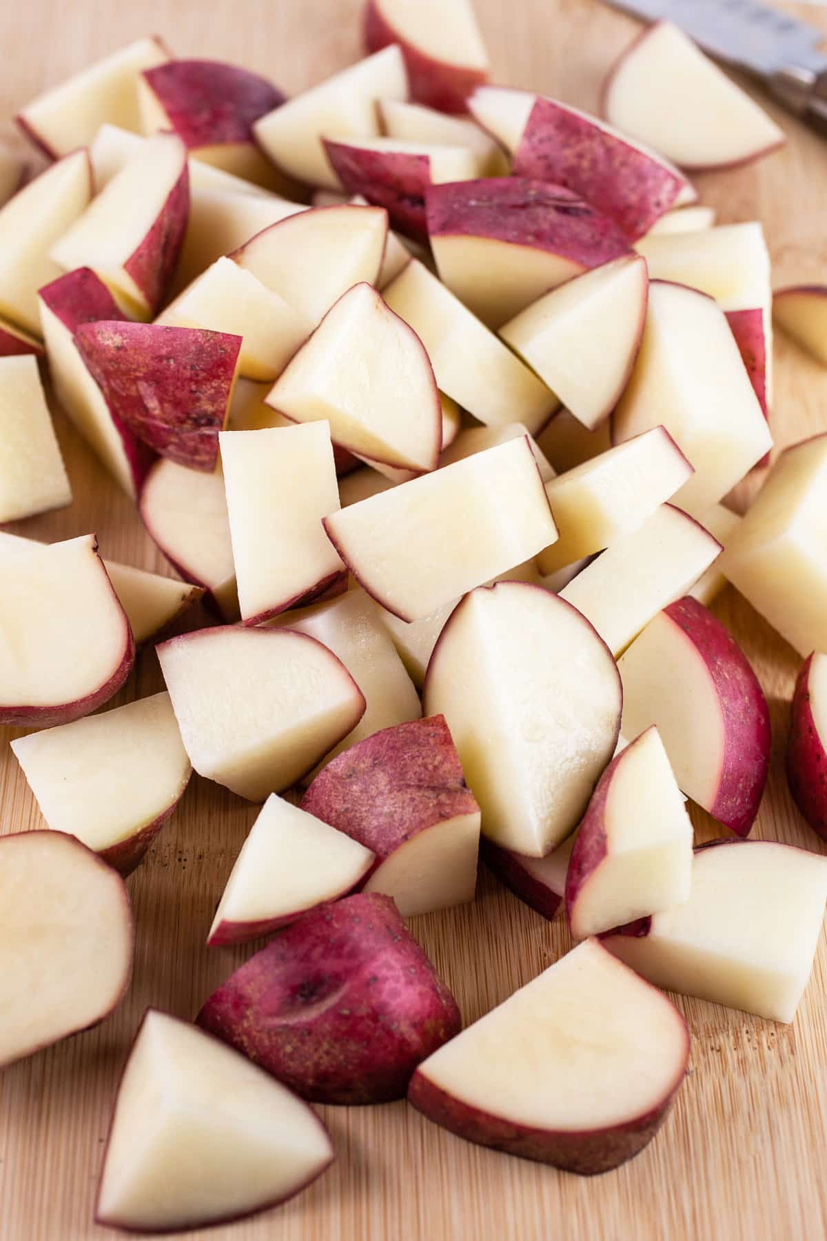 Diced red potatoes on wooden cutting board.