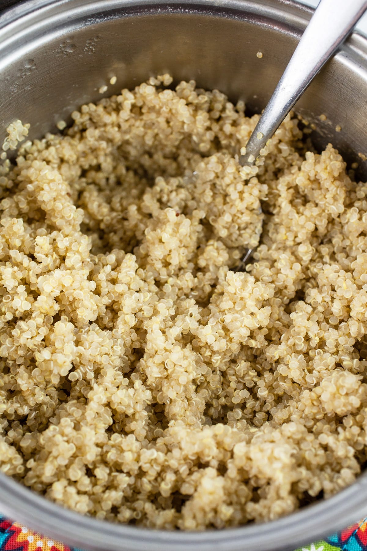 Cooked quinoa in small pan with spoon.