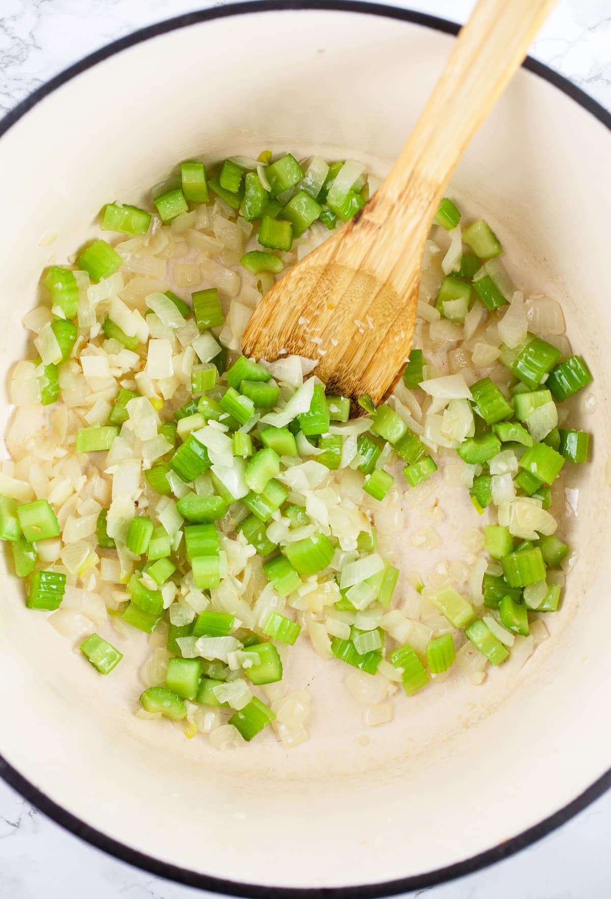 Minced garlic, onions, and celery sautéed in Dutch oven with wooden spoon. 