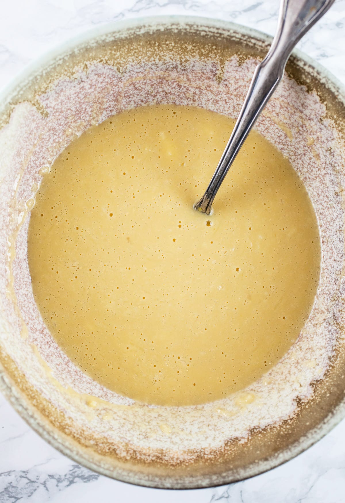 Wet ingredients in ceramic bowl with fork.