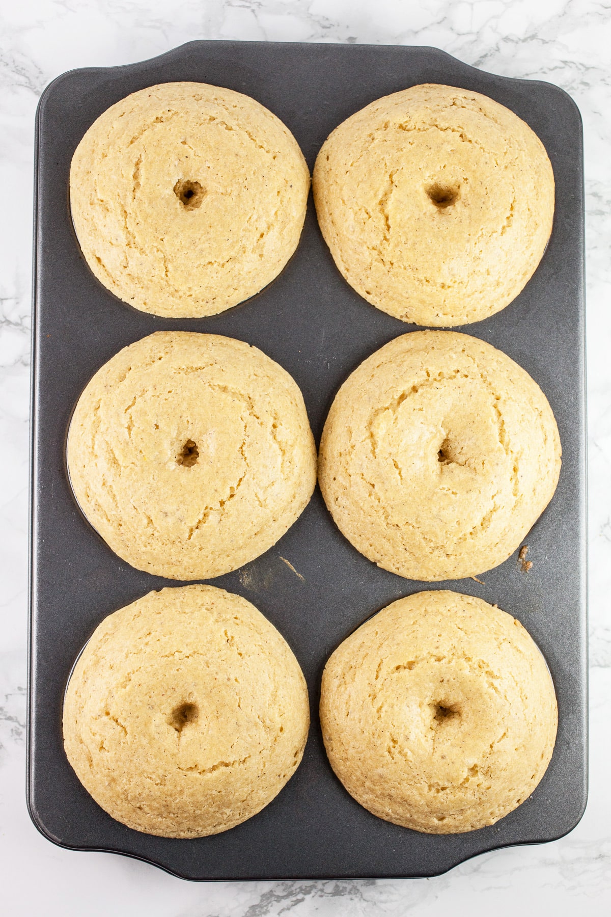 Baked doughnuts in metal doughnut pan.