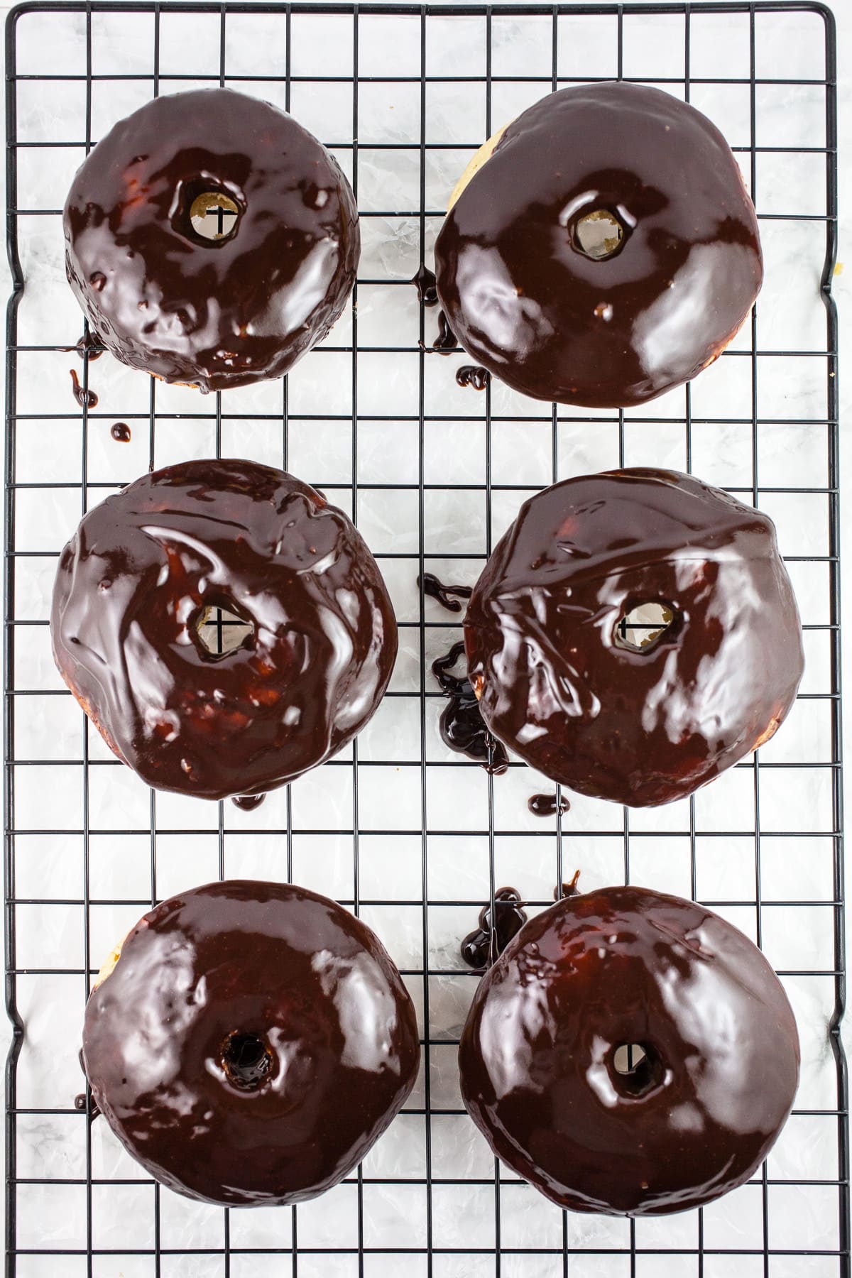 Chocolate dipped doughnuts on cooling rack.