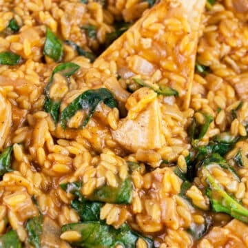 Cajun chicken orzo spinach pasta with wooden spoon.