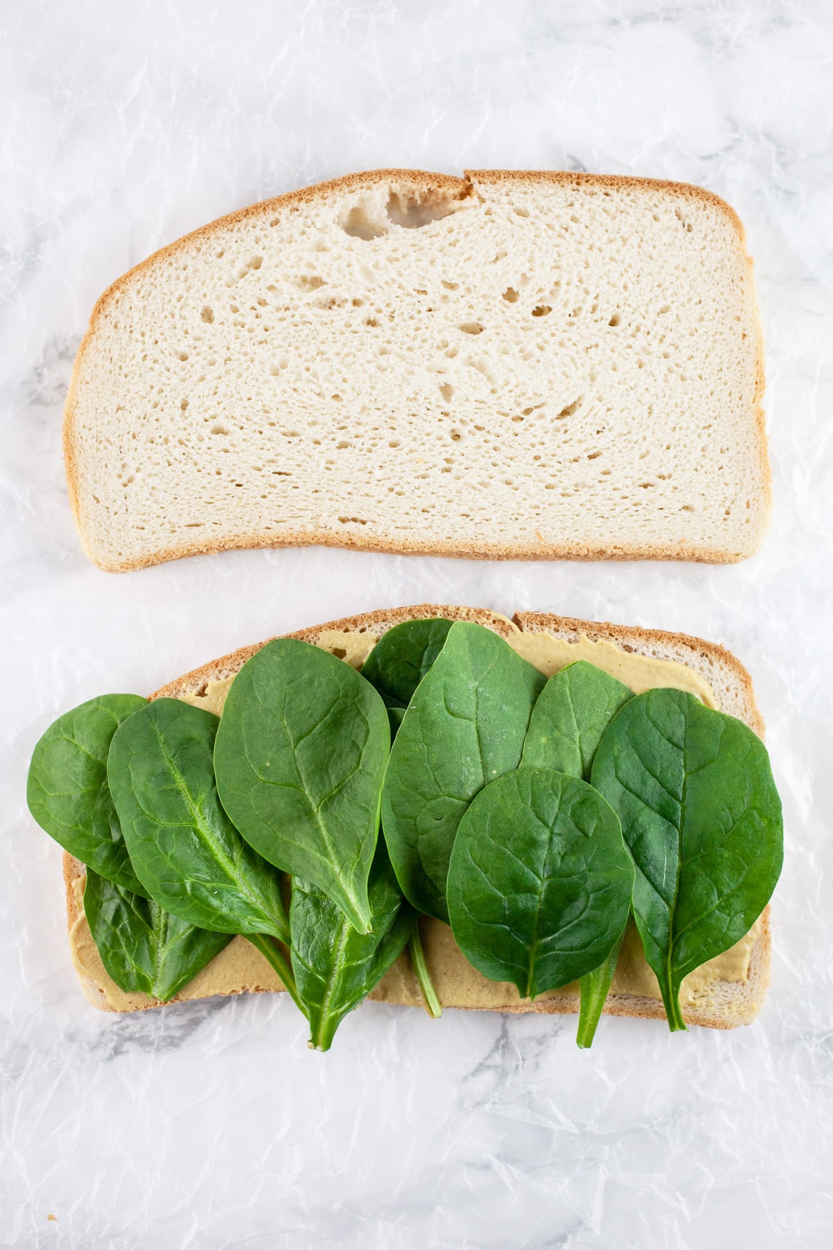 Sliced bread with mustard and fresh spinach.