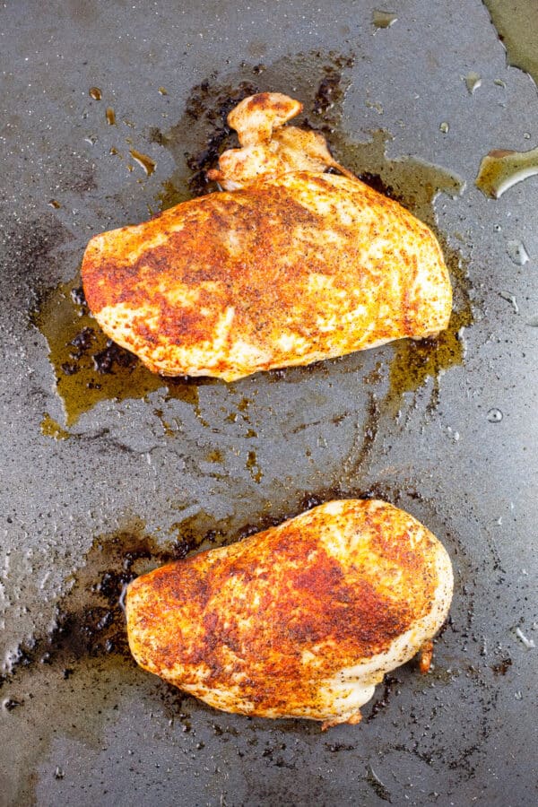 Spiced roasted chicken breasts on baking sheet.