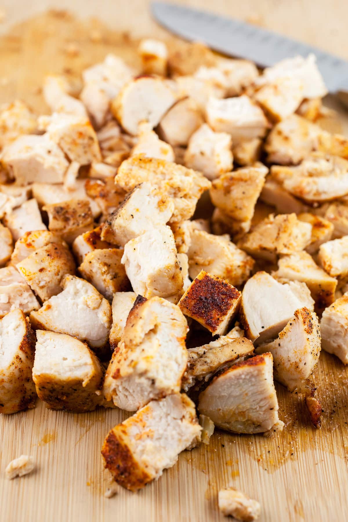 Diced roasted chicken breasts on wooden cutting board.