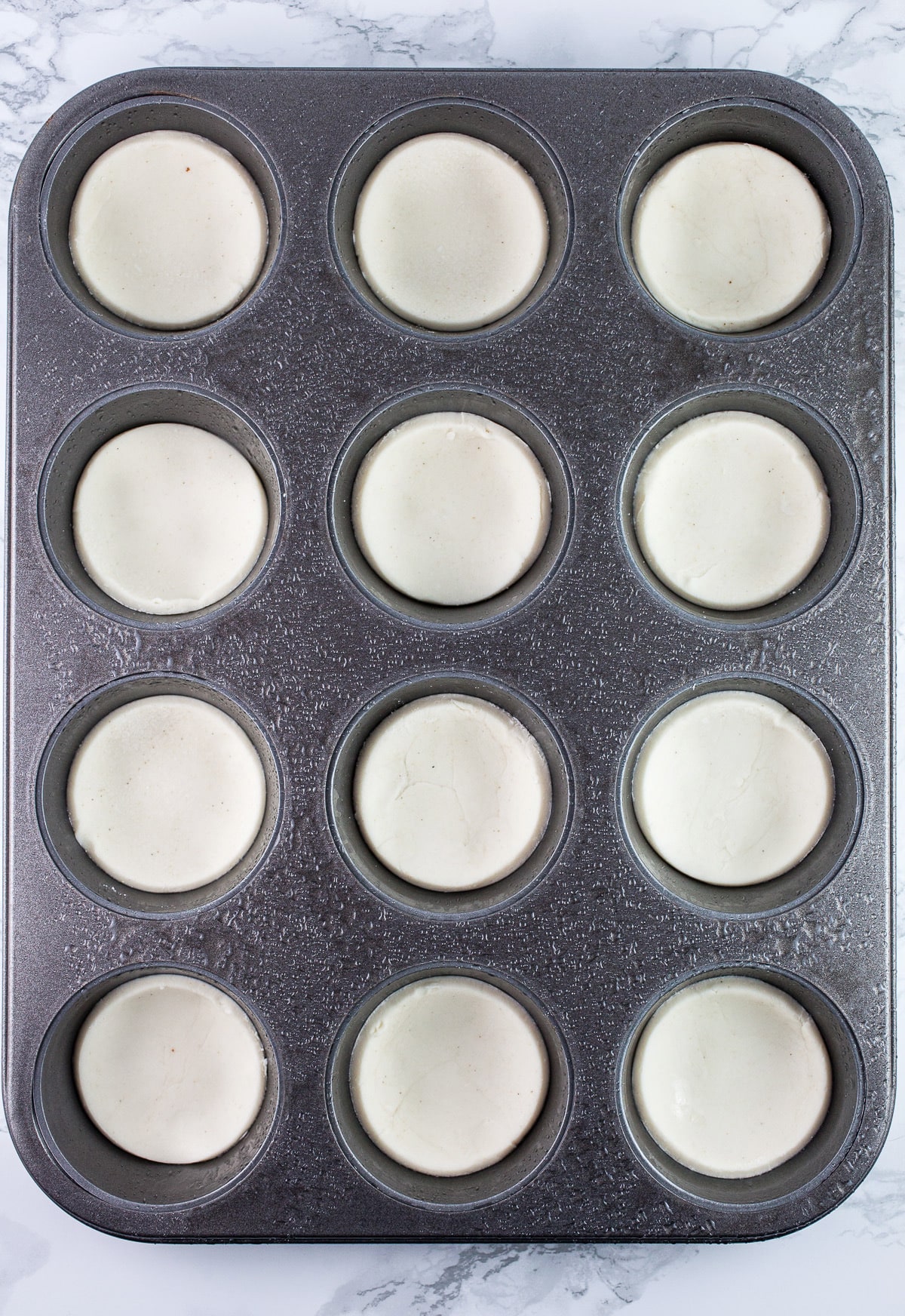 Uncooked Puff Pastry tartlets in muffin tin.
