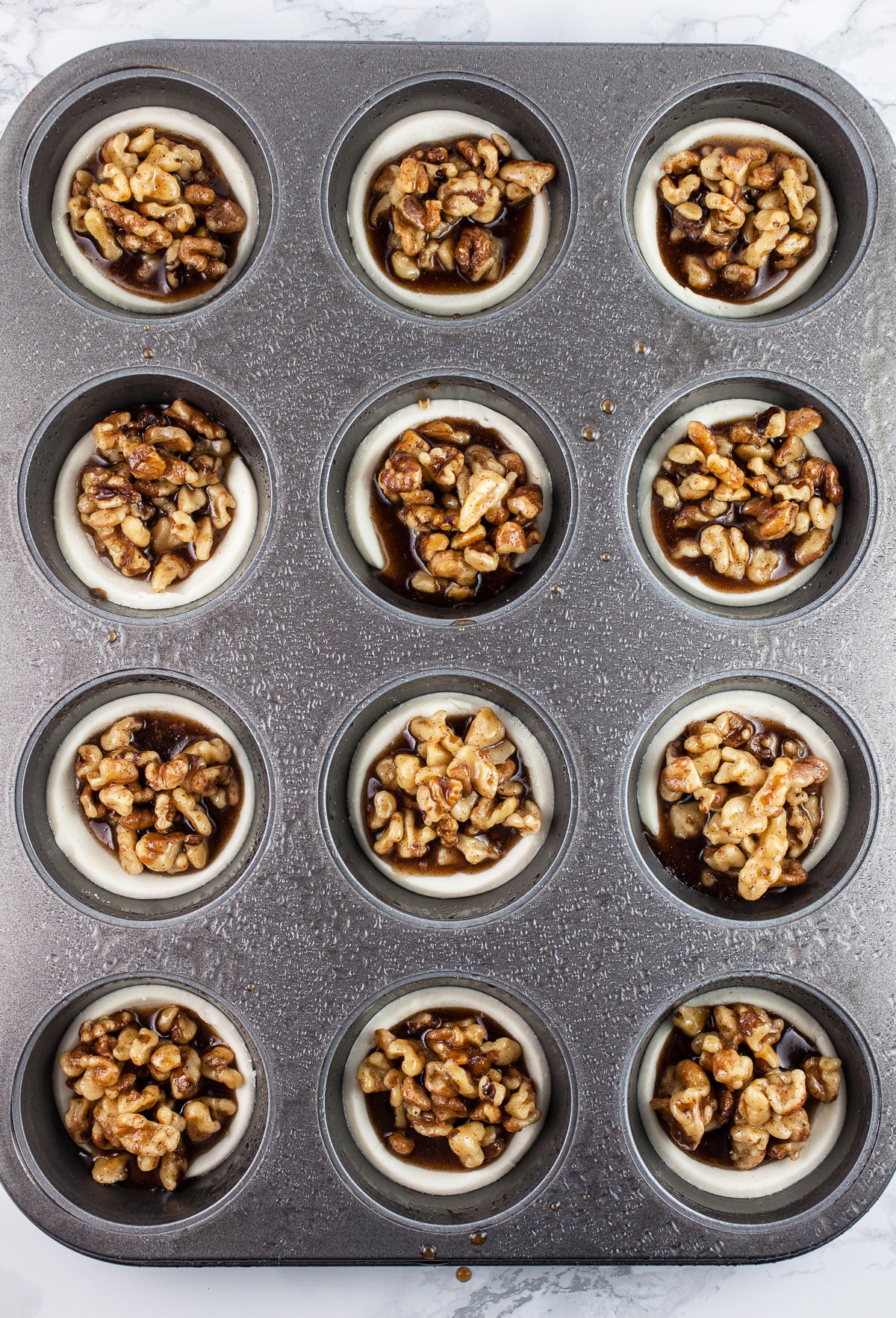Unbaked maple walnut baklava tartlets in muffin tin.