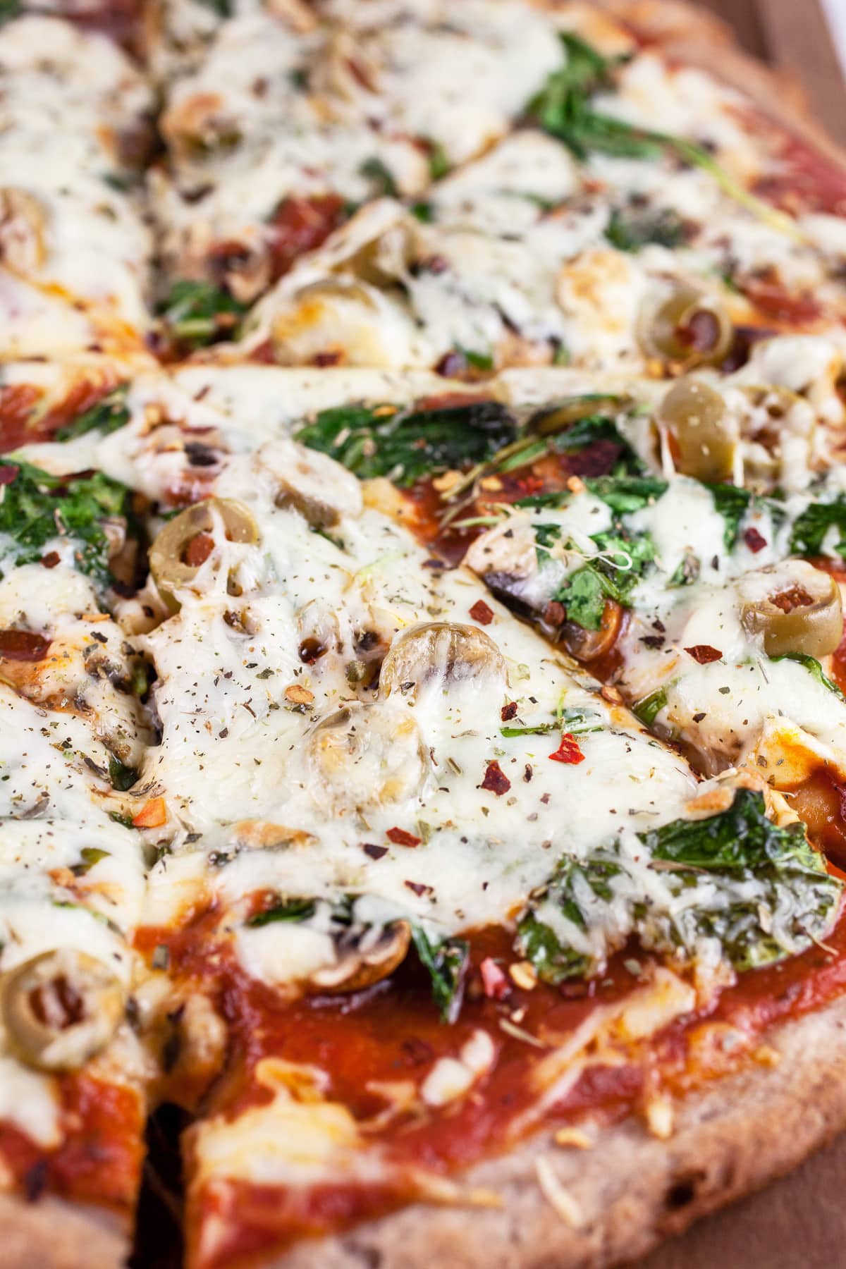 Mushroom arugula pizza with olives and mozzarella cheese cut into slices.