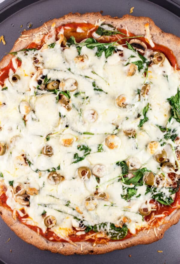 Baked mushroom arugula pizza on pizza crust.