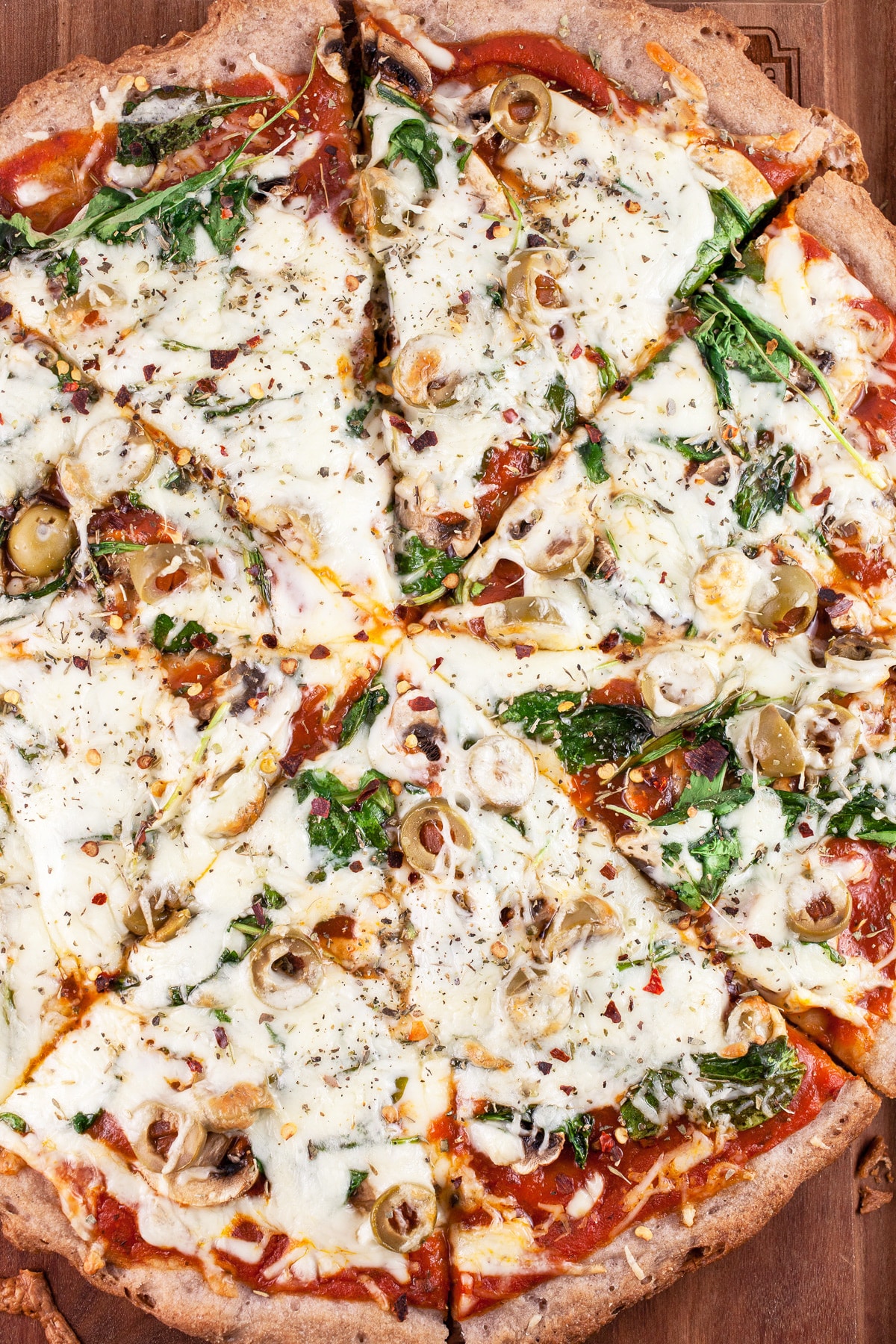 Sliced mushroom arugula pizza on wooden cutting board.