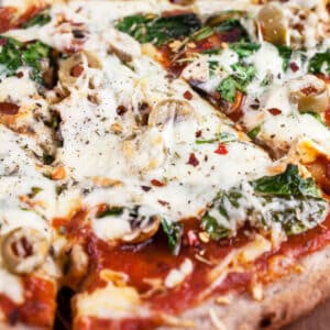 Sliced mushroom arugula pizza with mozzarella cheese and olives.