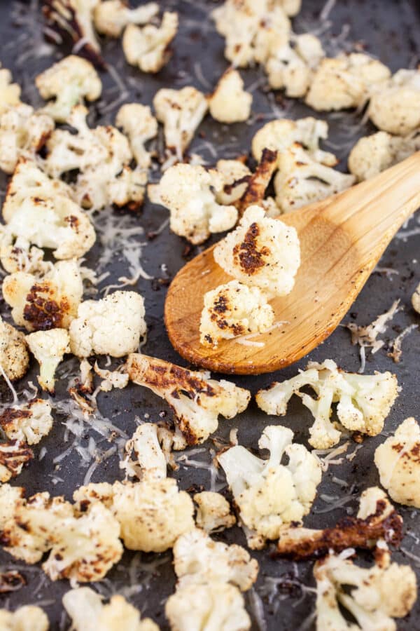 Parmesan roasted cauliflower on baking sheet with wooden spoon.