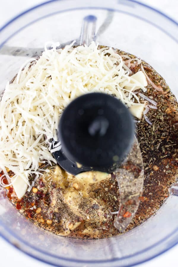 Olive oil, red wine vinegar, Dijon mustard, garlic cloves, spices, and grated Parmesan cheese in food procssor.