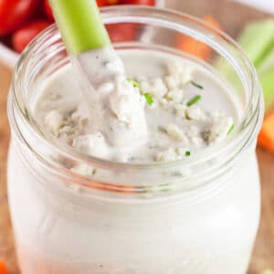 Celery stick dipped into jar of blue cheese dressing.