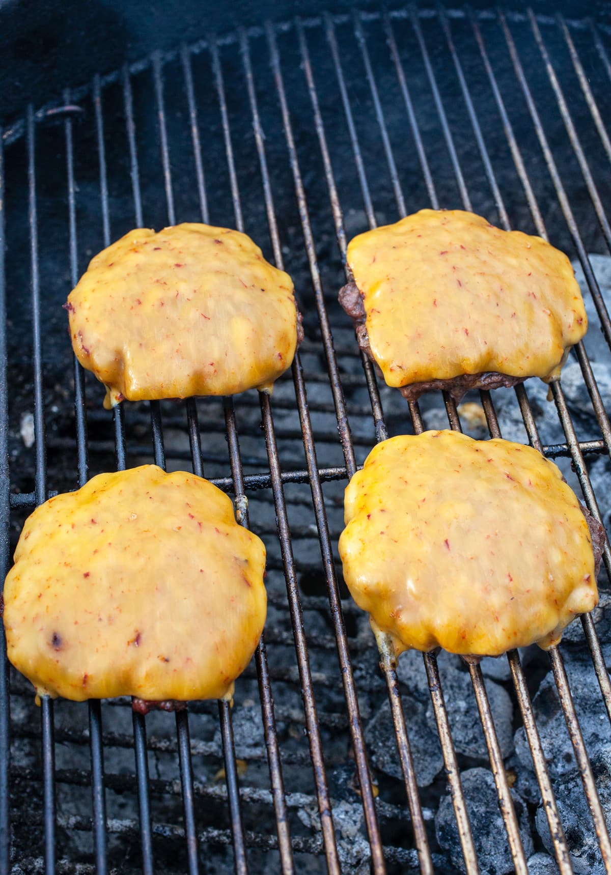Grilled burgers with cheese on charcoal grill.