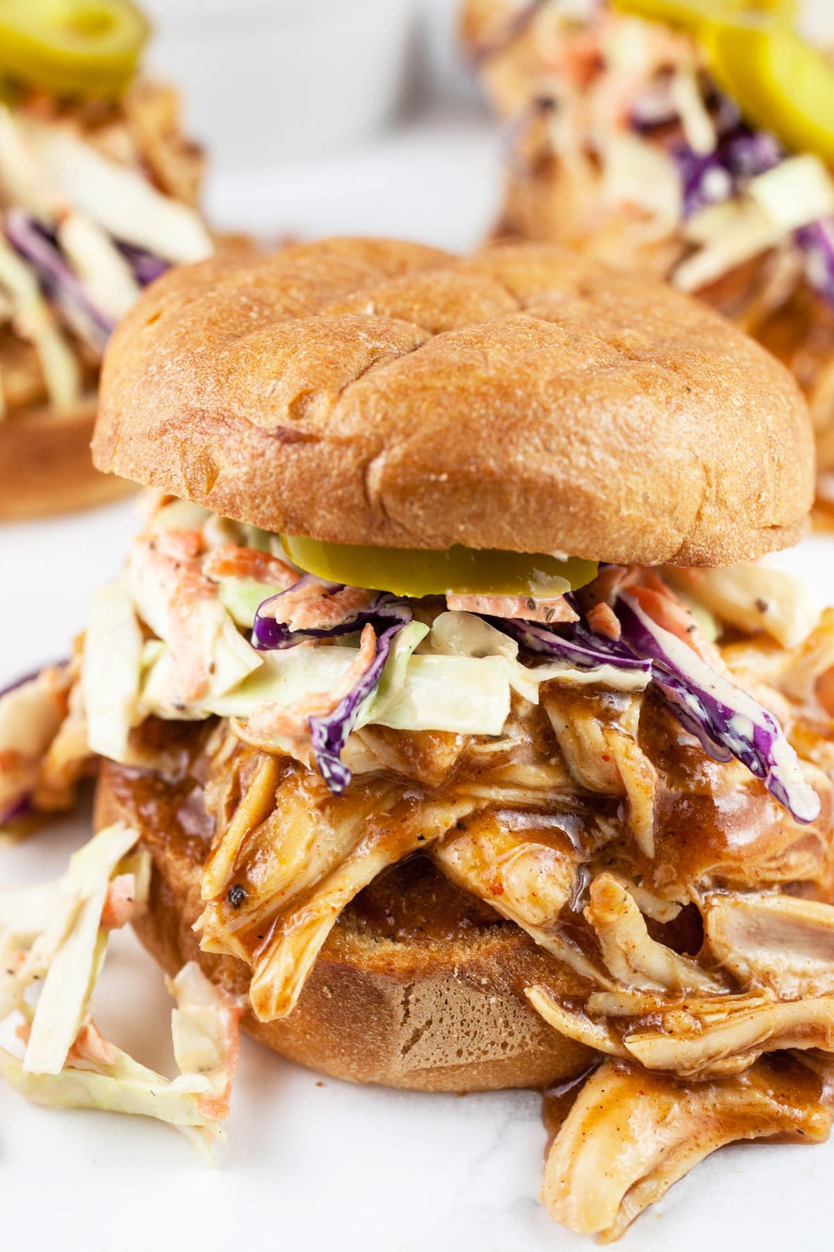 These Slow Cooker BBQ Chicken Sandwiches make the best flavorful healthy and easy meal! The chicken is made in the crockpot, shredded, and then finished in a tangy barbeque sauce. The chicken sandwich is topped with coleslaw. This is one of those great crock pot recipes to have on hand. It's a dinner the whole family will love! #bbq #chicken #sandwich #coleslaw #slowcooker #crockpot Shredded BBQ chicken sandwiches with coleslaw on toasted buns.
