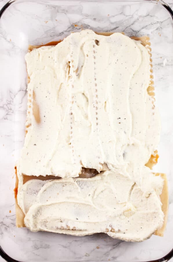 Ricotta cheese mixture spread onto lasagna noodles in glass baking dish.