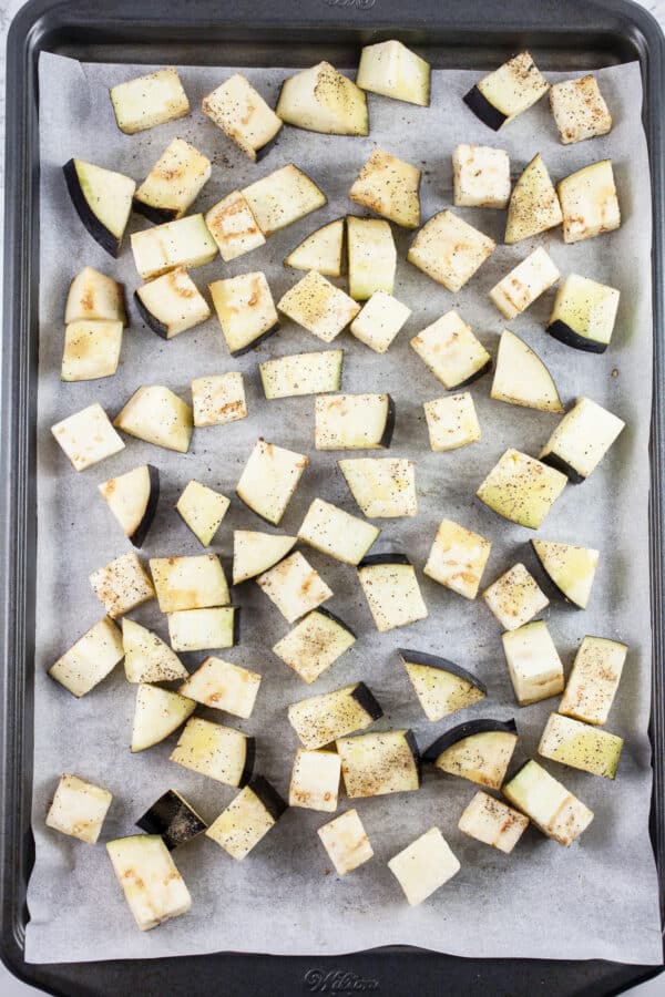 Uncooked eggplant cubes on baking sheet with parchment paper.