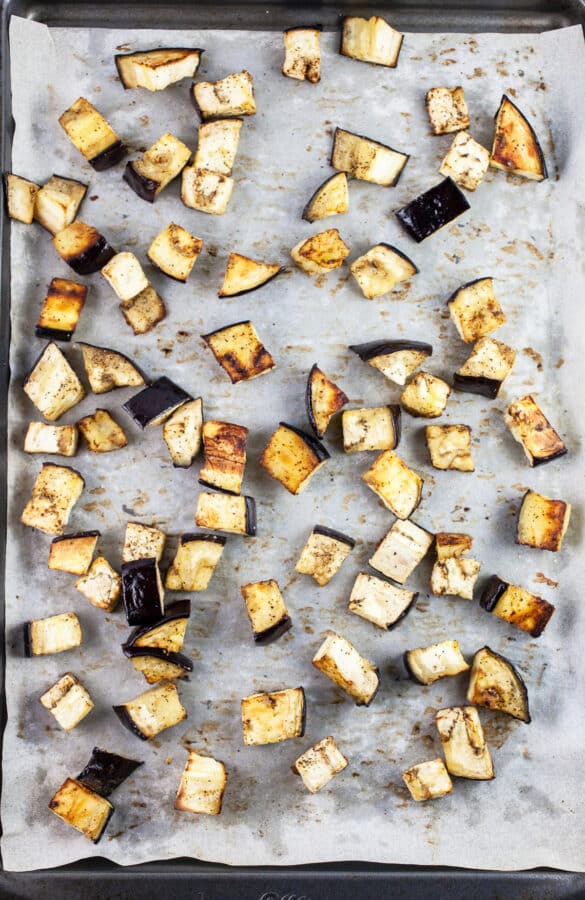 Roasted eggplant cubes on baking sheet with parchment paper.