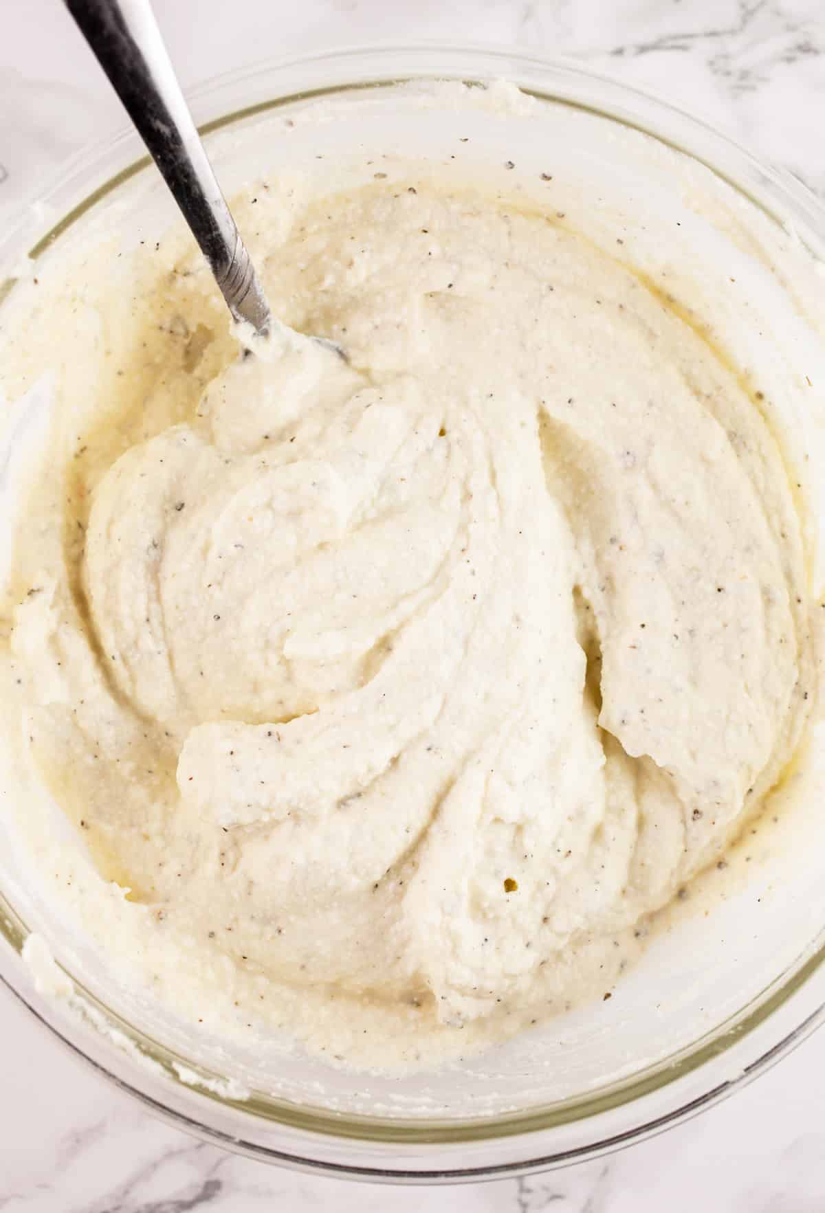 Ricotta cheese mixture in small glass bowl with fork.