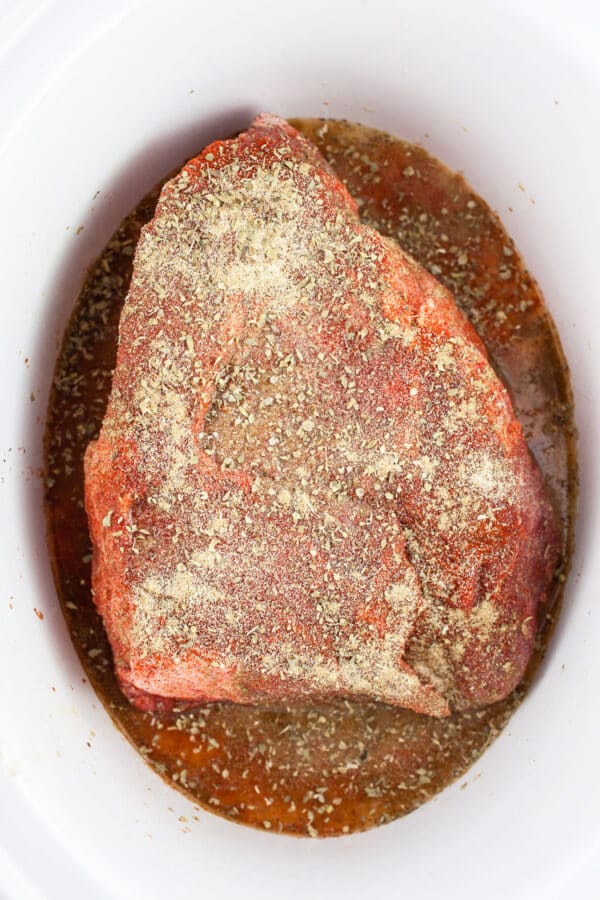 Uncooked spiced beef chuck roast in slow cooker.