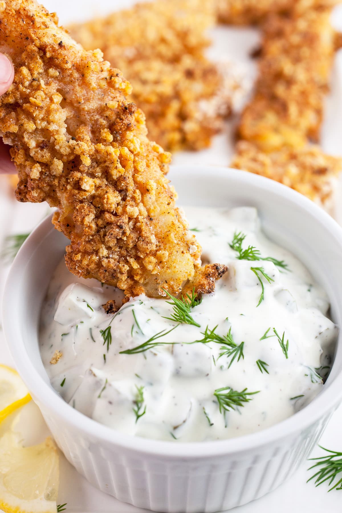This is the best Easy Homemade Tartar Sauce Recipe! Making your own tartar sauce is simple and tastes way better than store-bought. This fast recipe is made with pickles and mayonnaise. It goes great with fried fish and on sandwiches. Learn how to make this easy sauce! #tartarsauce #homemade #easy #fish #seafood Walleye fingers dipped into small bowl of dill tartar sauce.