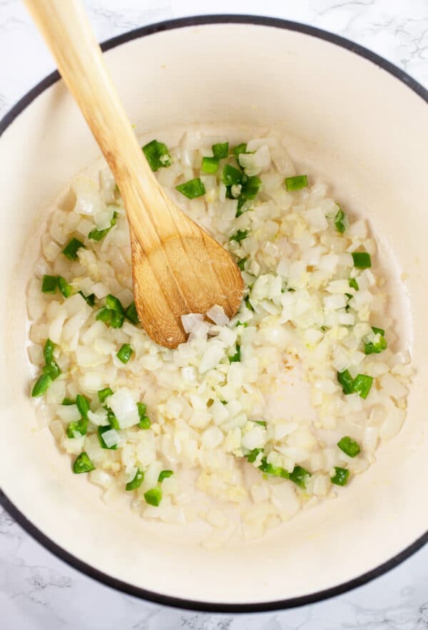 Minced garlic, onions, and jalapeno peppers sautéed in Dutch oven with wooden spoon.