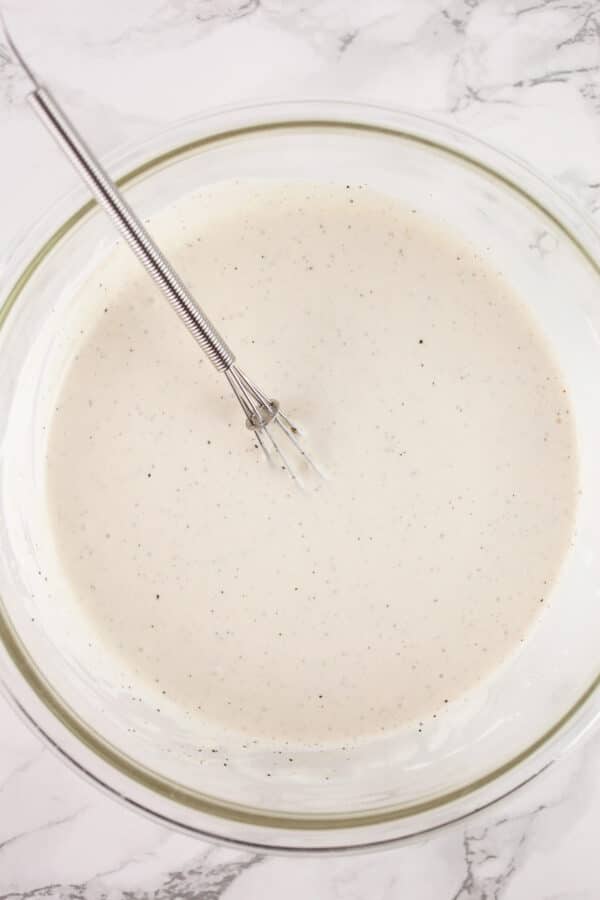 Sour cream and mayo combined in glass bowl with small whisk.