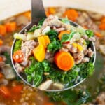 Scoop of fennel sausage soup lifted from Dutch oven on metal ladle.