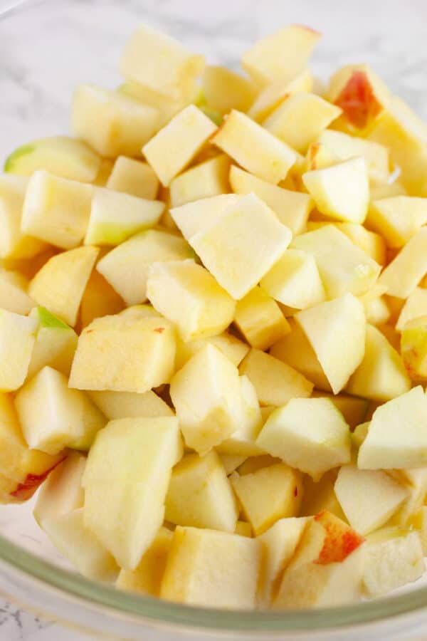 Raw diced apples in large glass mixing bowl.