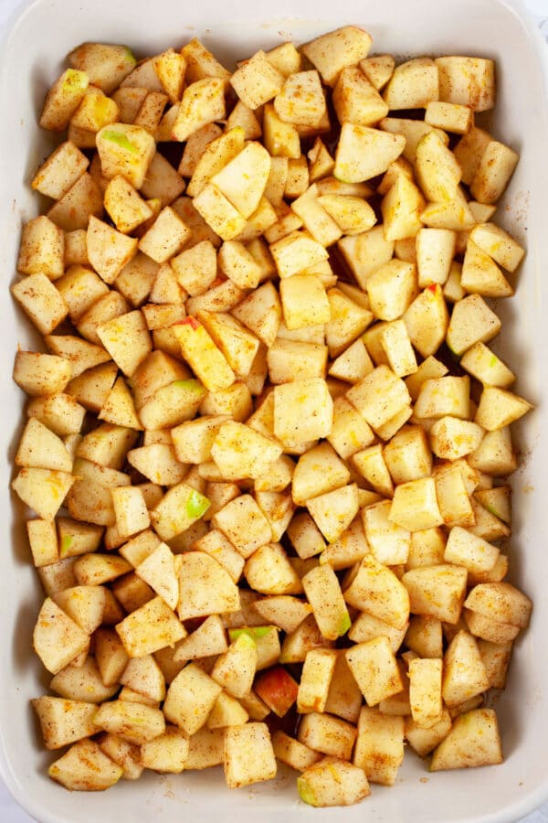 Uncooked apples in ceramic baking dish.