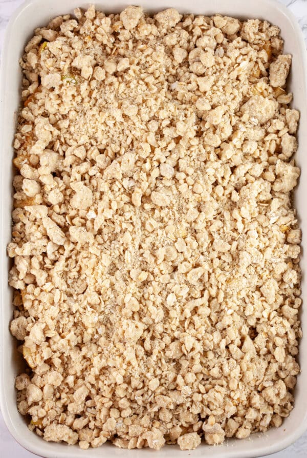 Uncooked apple crisp in ceramic baking dish.